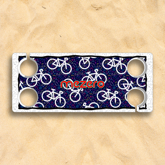 Biker – Rugged Style & Power for Every Ride or Street Step beach table with white bicycle pattern, four cup holders, and Mezero branding on sand.